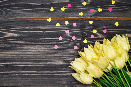 Spring background with bunch of tulip flowers corner with pink heart sprinkles on wood background, copy space. Flat lay. Greeting card for Valentine's Day, Woman's Day (March 8), Mother's Day, Easter