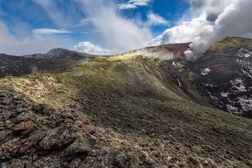 Yellow rim of the main summit crater Voragine of mount Etna, Sicily, Italy, with toxic sulfur gas clouds.