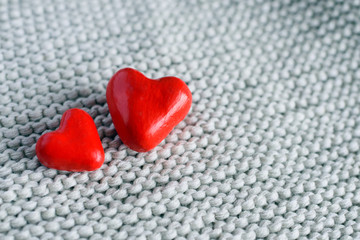 two red hearts close-up on knitted background.