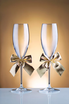 Festive champagne glasses with golden bows on a glass table