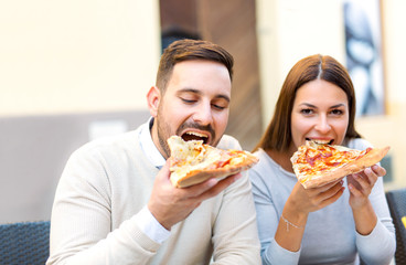 Couple eating pizza snack outdoors.