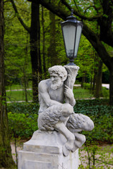 Fototapeta premium Baroque Statue of a Satyr or Faun holding a Lantern in a Park
