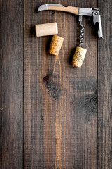 Open wine bottle. Corks and corkscrew on dark wooden background top view copyspace