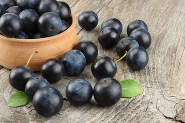 blackthorn berries with green leaf on old wooden table