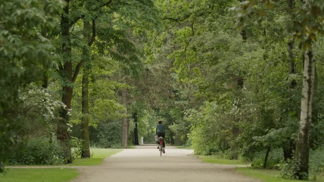 Wide shot of man riding bicycle in park / Berlin, Germany