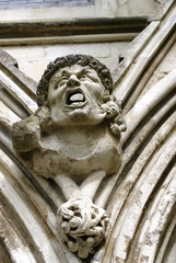 Gargoyle with hideous face and open moutn above the West Door of Salisbury Cathedral, Great Britain