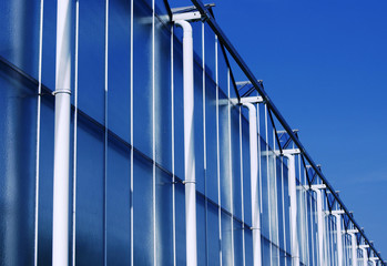 Fototapeta na wymiar Greenhouse exterior with rainpipes and reflection of the blue sky in windows. The Netherlands, Europe