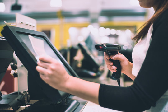 Young woman hands scaning / entering discount / sale on a receipt, touchscreen cash register, market / shop (color toned image)