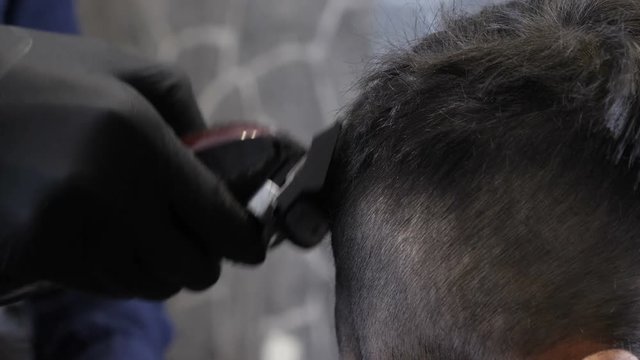 Barber in black gloves shaves the child's nepe, close up 60 fps