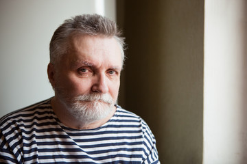 Serious adult man with grey hair looking into the camera