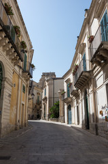 Naklejka na ściany i meble Narrow scenic street in Ragusa, Sicily, Italy with old townhouses
