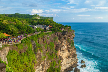 View of Uluwatu cliff with tourists, pavilion and blue sea in Bali, Indonesia