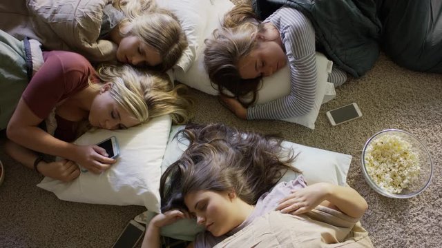Medium high angle shot of girls sleeping on floor at slumber party / Cedar Hills, Utah, United States