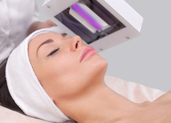 The cosmetologist uses the Wood Lamp for detailed diagnosis of the skin condition. The device detects the presence of skin diseases or inflamed areas. Cosmetology and professional care.