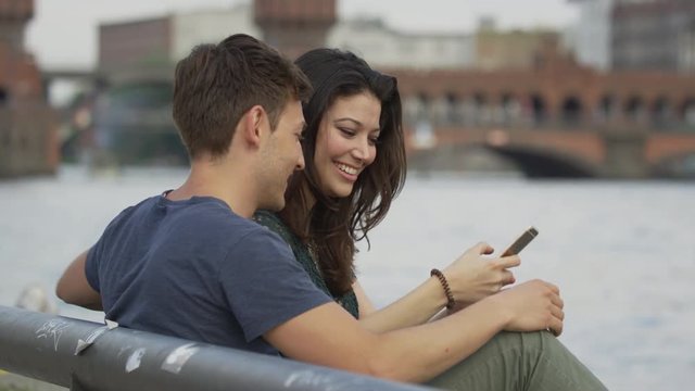 Close up of couple at waterfront posing for cell phone selfie / Berlin, Germany