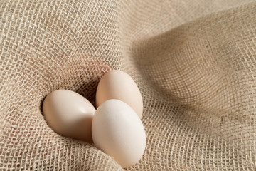 three chicken eggs on a linen burlap