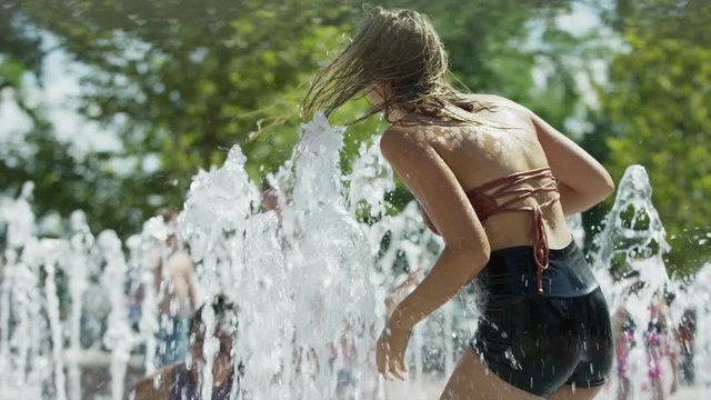 Girls spinning and splashing in park fountain / Provo, Utah, United States