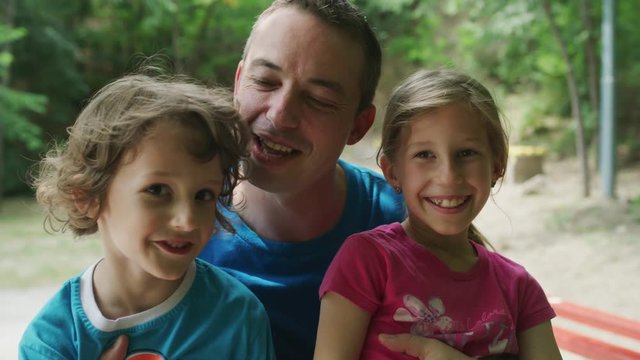Close up slow motion panning shot of father hugging children in park / Plovdiv, Bulgaria