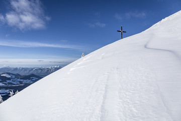 Fototapeta na wymiar Gipfelkreuz im Winter mit Schnee unter blauem Himmel