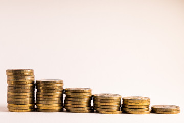 Stacks of coins on white background different heights, reducing the income of the business