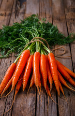Bunch of fresh carrots with green leaves over wooden background. Vegetable.Food or Healthy diet concept.Vegetarian.Copy space for Text. selective focus.