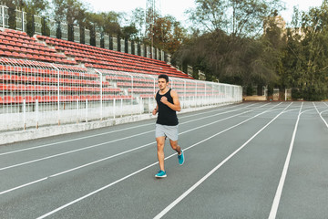 Fototapeta premium Young athletic man running on the stadium in the morning