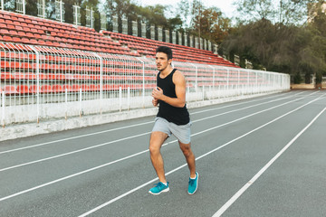 Fototapeta na wymiar Young athletic man running on the stadium in the morning