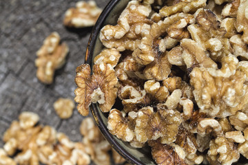 Bowl of Shelled Walnuts Spilling Over Onto a Rustic Tree Stump