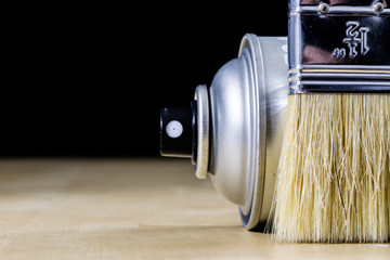 Pedzel for painting with oil paint on a wooden workshop table and a spray can. A bristle brush in a workshop.
