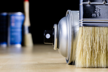 Pedzel for painting with oil paint on a wooden workshop table and a spray can. A bristle brush in a workshop.