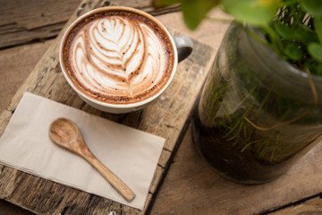 Cup of hot latte art coffee on wooden table