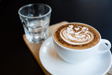 Cup of hot latte art coffee on black table