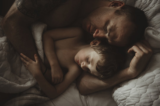 High angle view of father and son sleeping on bed - Powered by Adobe
