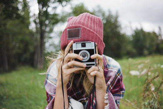 Woman photographing with instant camera on grassy field