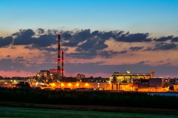 Fototapeta premium Night industrial landscape. Glowing factories in the city.