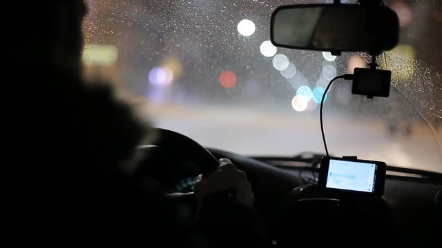 A man gets into the car and turns on the navigator on the smartphone