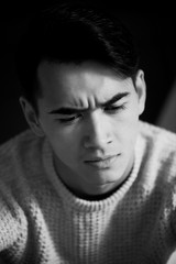 A young man with dark hair and eyes frowns. Reverie