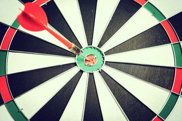 Dart arrow hitting in the target center of dartboard