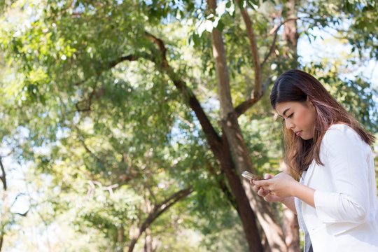 An Asian woman is using mobile phone in the park