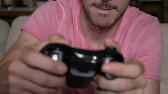 Closeup of competitive focused guy working out winning video game session controlling remote buttons in slowmo
