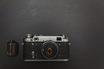 Vintage Film Camera And Roll On Black Wooden Background Technology Development Photographer Concept with copy space. Top View