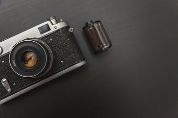 Vintage Film Camera And Roll On Black Wooden Background Technology Development Photographer Concept...