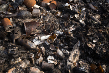 Broken glass bottles and garbage in burned trash