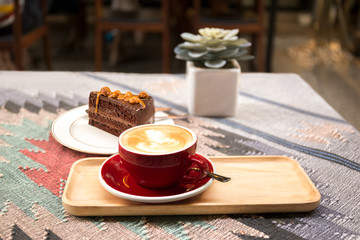 Obraz na płótnie Canvas Cup of coffee and piece of macadamia chocolate cake