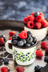 Fresh ripe blueberry and raspberry in mugs