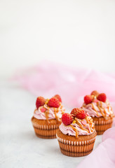 Raspberry and caramel cupcakes on white background