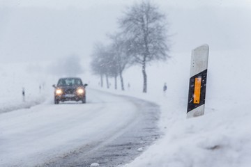 Auto Verkehr auf glatter gefrorener Winter Straße mit Eis Schnee. Die Fahrbahn ist weiß glatt verschneit. Vorsicht vor Unfall durch Frost und schlechte Sicht. Wetter zur Weihnachten Jahreszeit