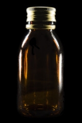 Transparent brown jar with a metal lid appears on a black background