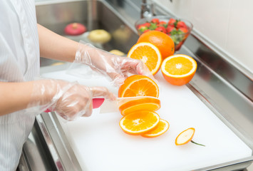 Female hands cutting fresh juicy orange on board