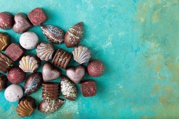 Colored chocolate candies. Creative sweets on a turquoise background.